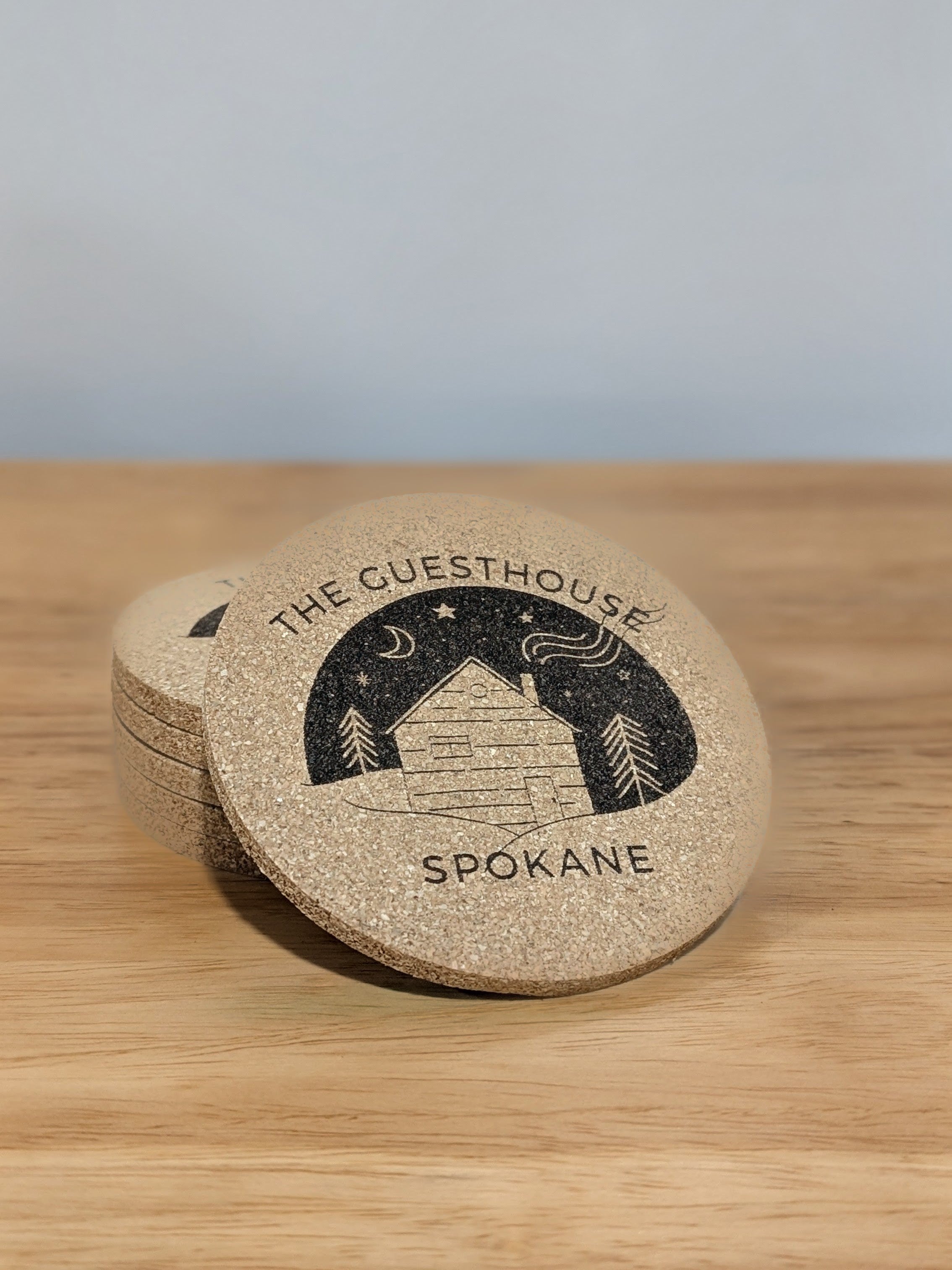 The Guesthouse logo custom laser engraved on a cork coaster. 